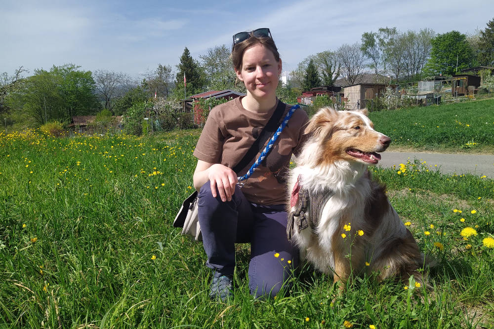 Karin Schlatter mit einem Australian Shepherd auf einer Wiese bei Schlieren